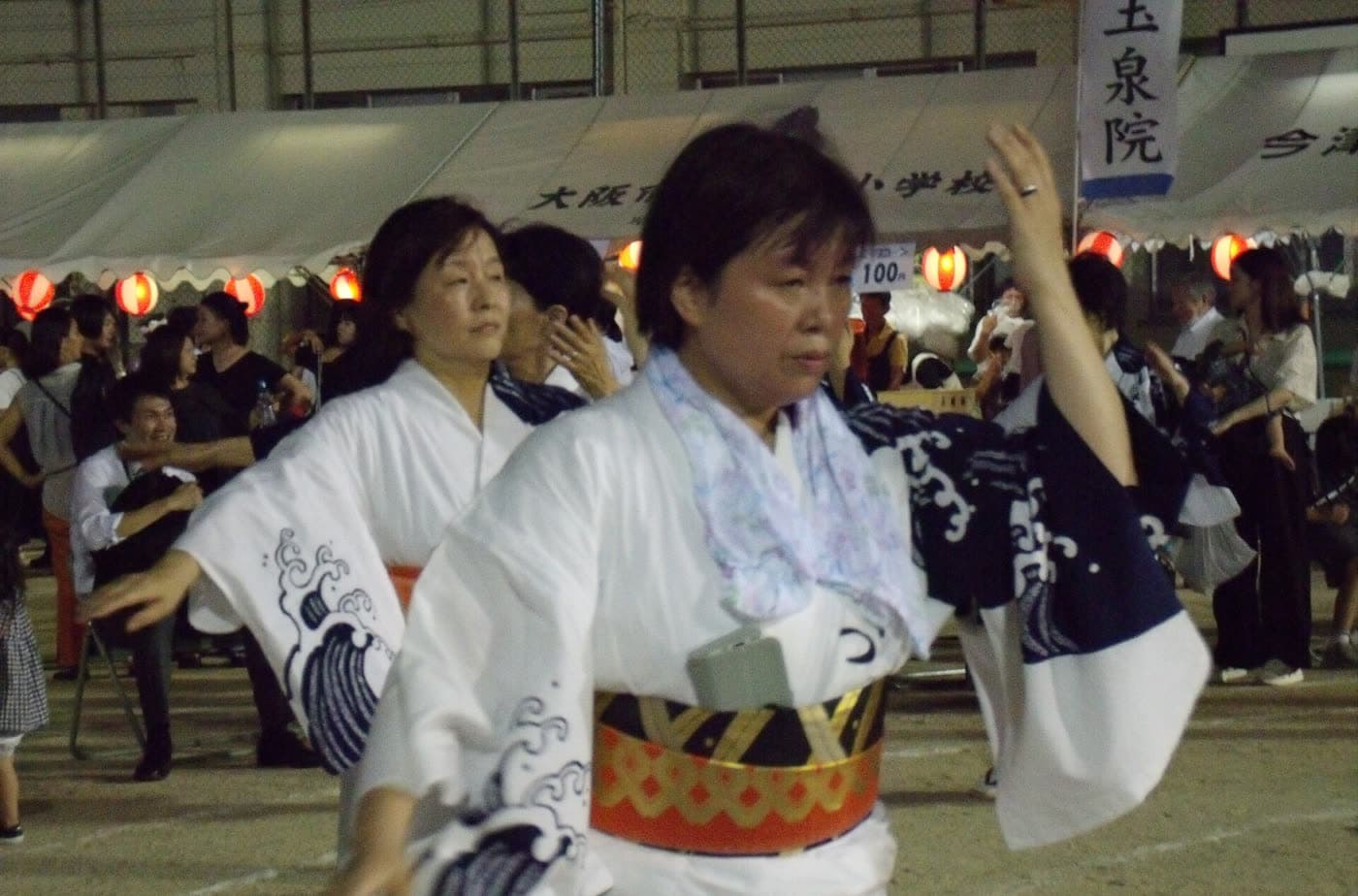 Woman dancing Bon Odori in a white yukata printed with waves